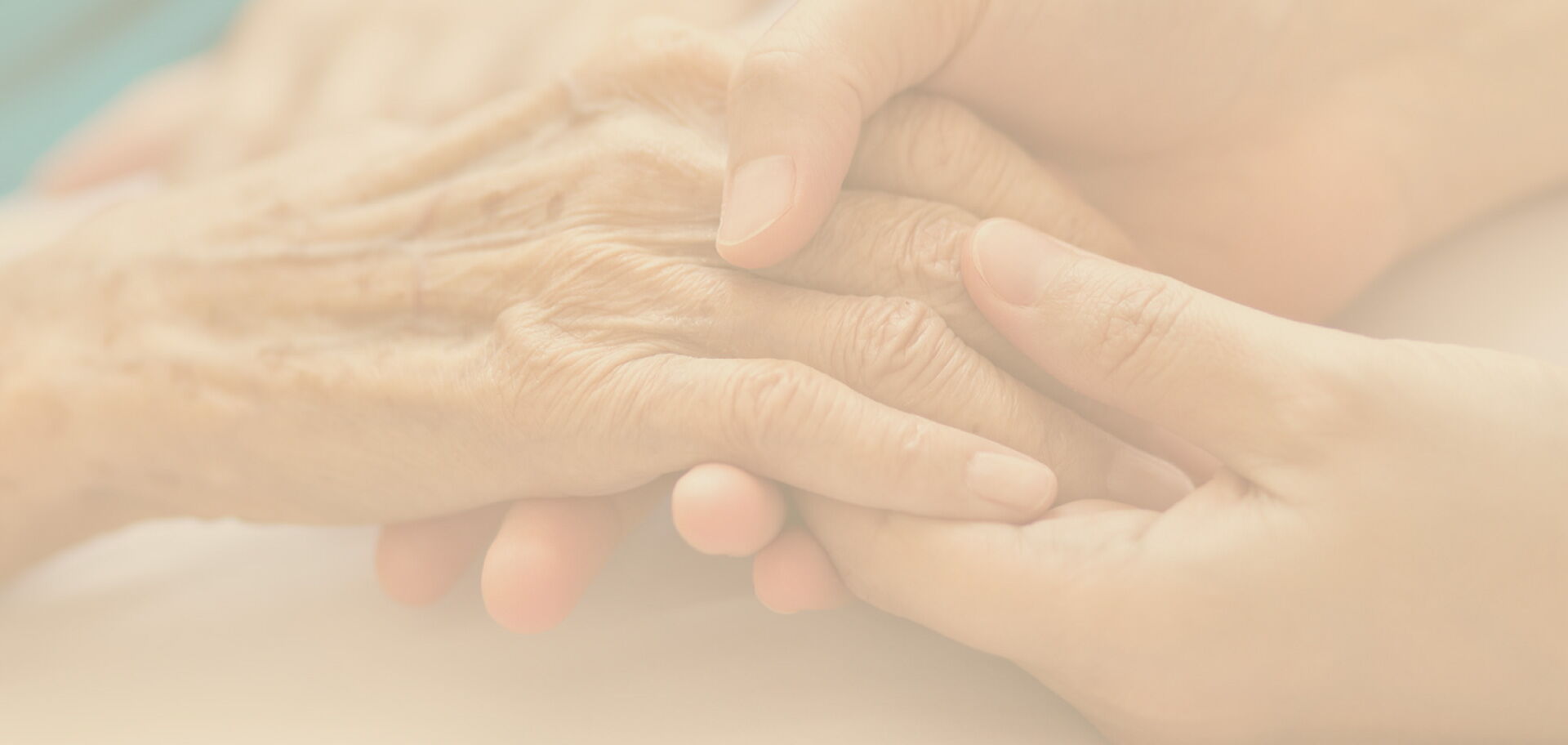 Sanft abgetönte Detailaufnahme einer jungen Hand, die eine ältere Hand hält – als atmosphärischer Hintergrund für Vertrauen und Pflege.