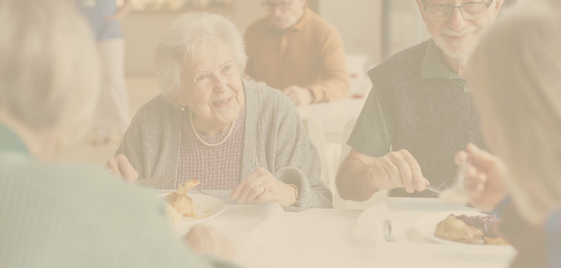 Dezent abgetöntes Hintergrundbild einer Seniorengruppe in geselliger Runde.