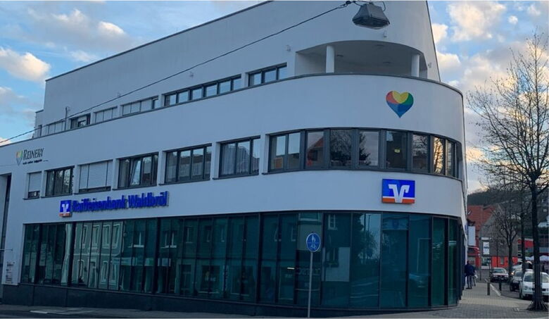 Die zentral gelegene Wohnanlage in Waldbröl mit moderner Architektur und dem weithin sichtbaren Reinery-Herz-Logo an der Fassade.